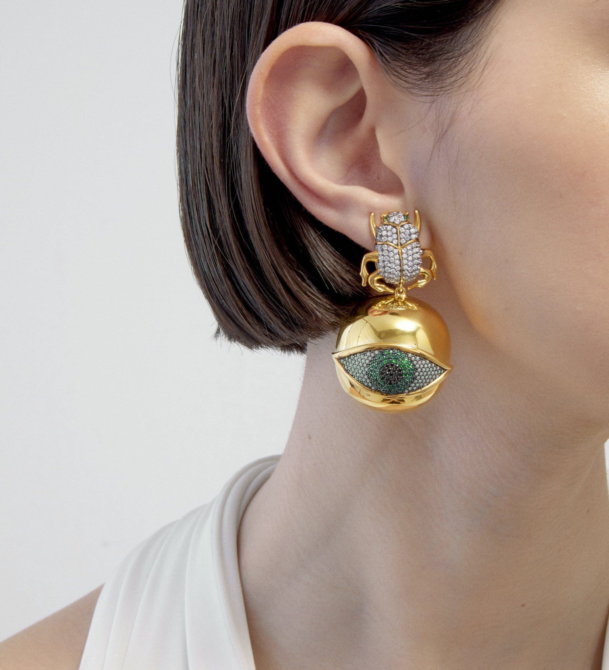 BEGÜM KHAN Scarab Goldeneye earrings with green crystal accents and gold plating, detailed close-up of the elegant jewelry.